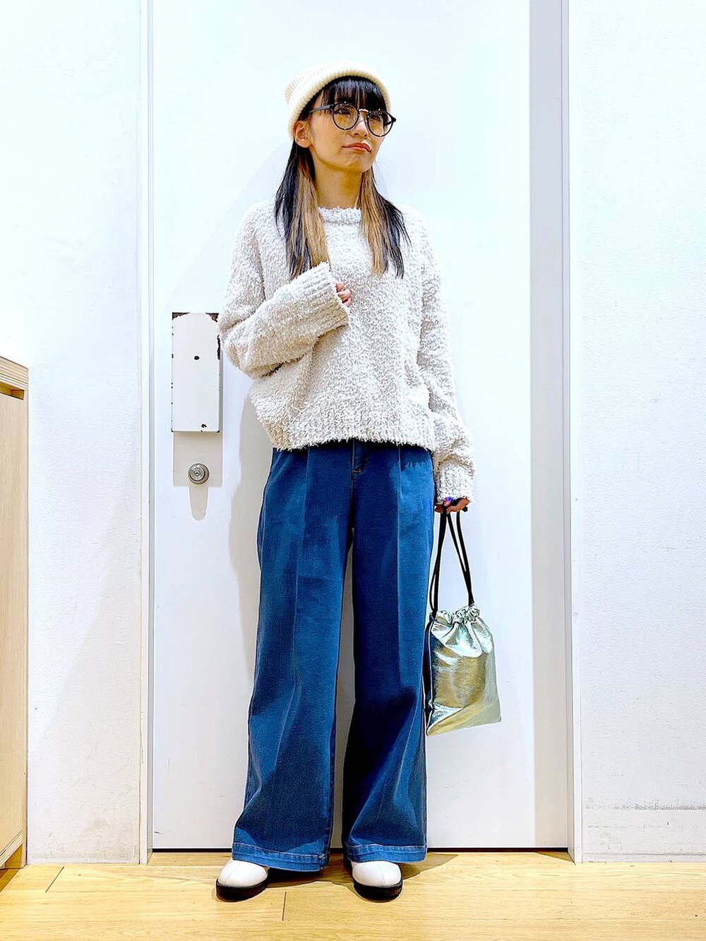 グレー系のニット/セーター、ブルー系のデニムパンツ、ベージュ系のブーツを着用したレディースの冬コーディネートの2枚目の写真