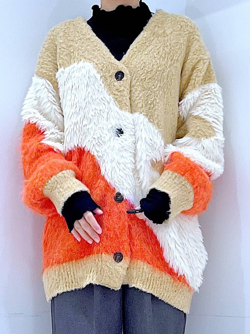 オレンジ系のカーディガン/ボレロ、ブラック系のブーツ、グレー系のスラックスを着用したレディースの冬コーディネートの7枚目の写真