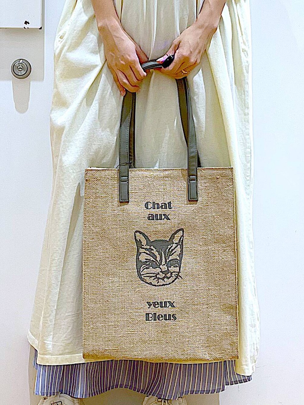 ホワイト系のサンダル、ベージュ系のワンピース、グレー系のトートバッグを着用したレディースの夏コーディネートの9枚目の写真