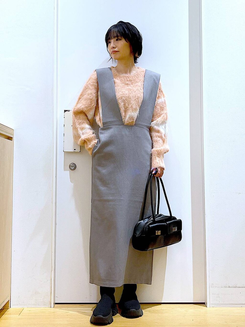 ピンク系のニット/セーター、ブラック系のハンドバッグ、ブラック系のブーツを着用したレディースの冬コーディネートの2枚目の写真