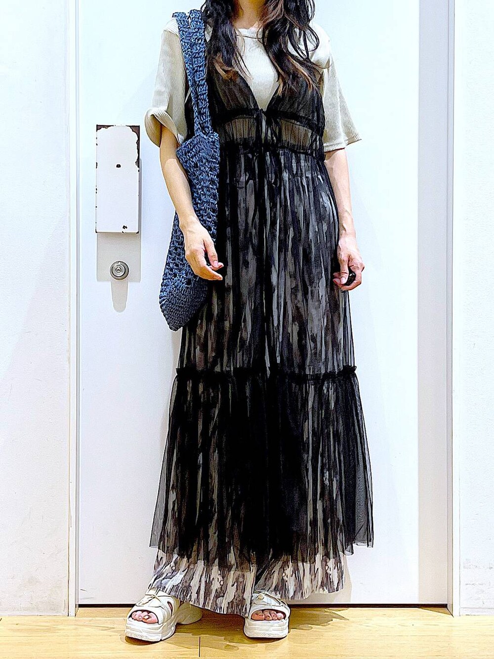 ブラック系のワンピース、ホワイト系のサンダル、ブルー系のトートバッグを着用したレディースの夏コーディネートの6枚目の写真