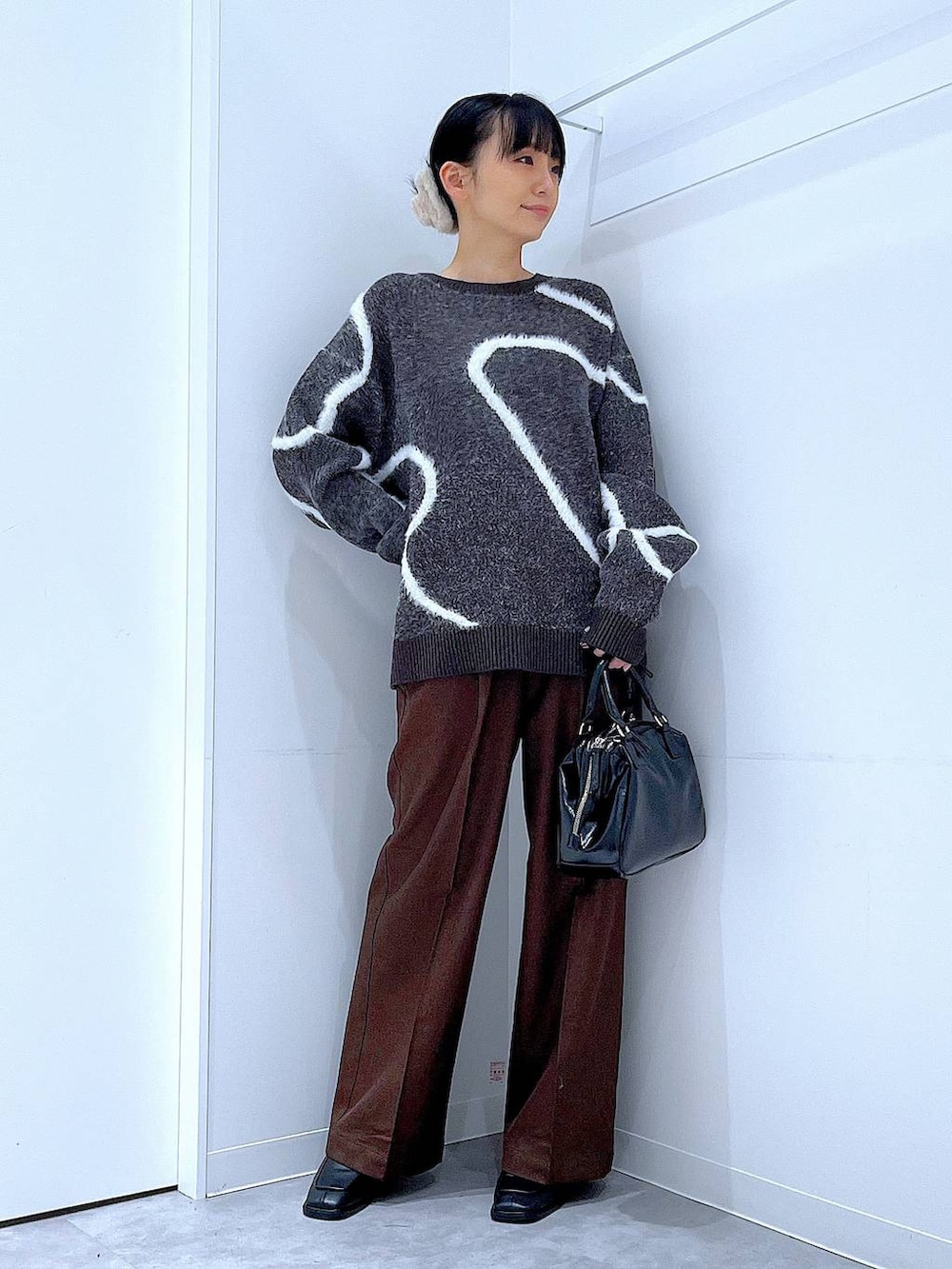 ブラック系のブーツ、ブラウン系のスラックス、ブラック系のショルダーバッグを着用したレディースの冬コーディネートの2枚目の写真