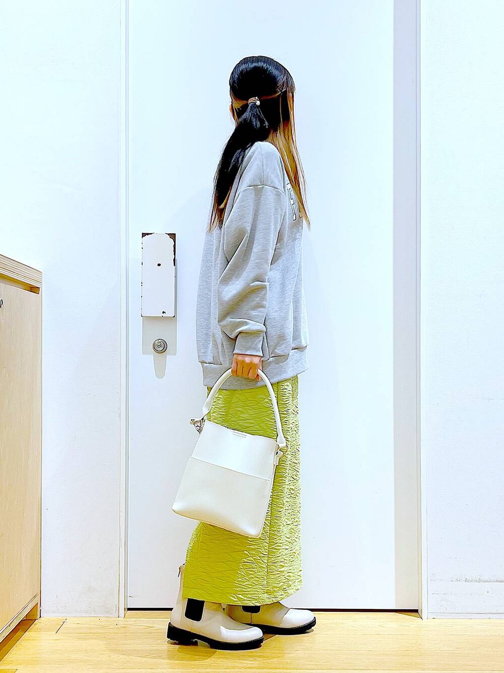 グリーン系のスカート、グレー系のスウェット、ホワイト系のショルダーバッグを着用したレディースの春コーディネートの4枚目の写真