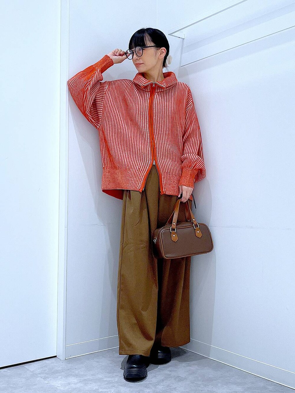 ブラック系のブーツ、オレンジ系のニット/セーター、ブラウン系のその他パンツを着用したレディースの冬コーディネートの2枚目の写真