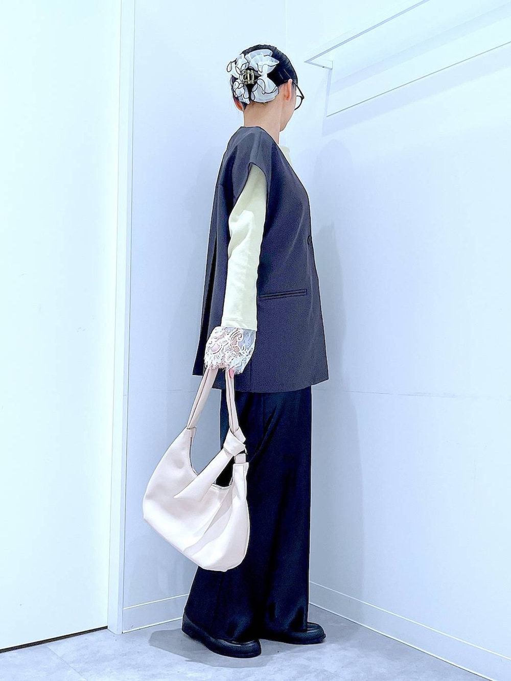 ブラック系のスカート、グレー系のベスト、ブラック系のローファーを着用したレディースの春コーディネートの4枚目の写真