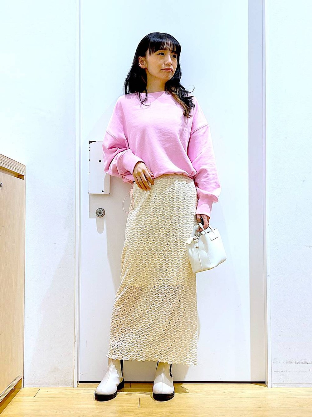 ピンク系のスウェット、ベージュ系のブーツ、ホワイト系のショルダーバッグを着用したレディースの春コーディネートの2枚目の写真