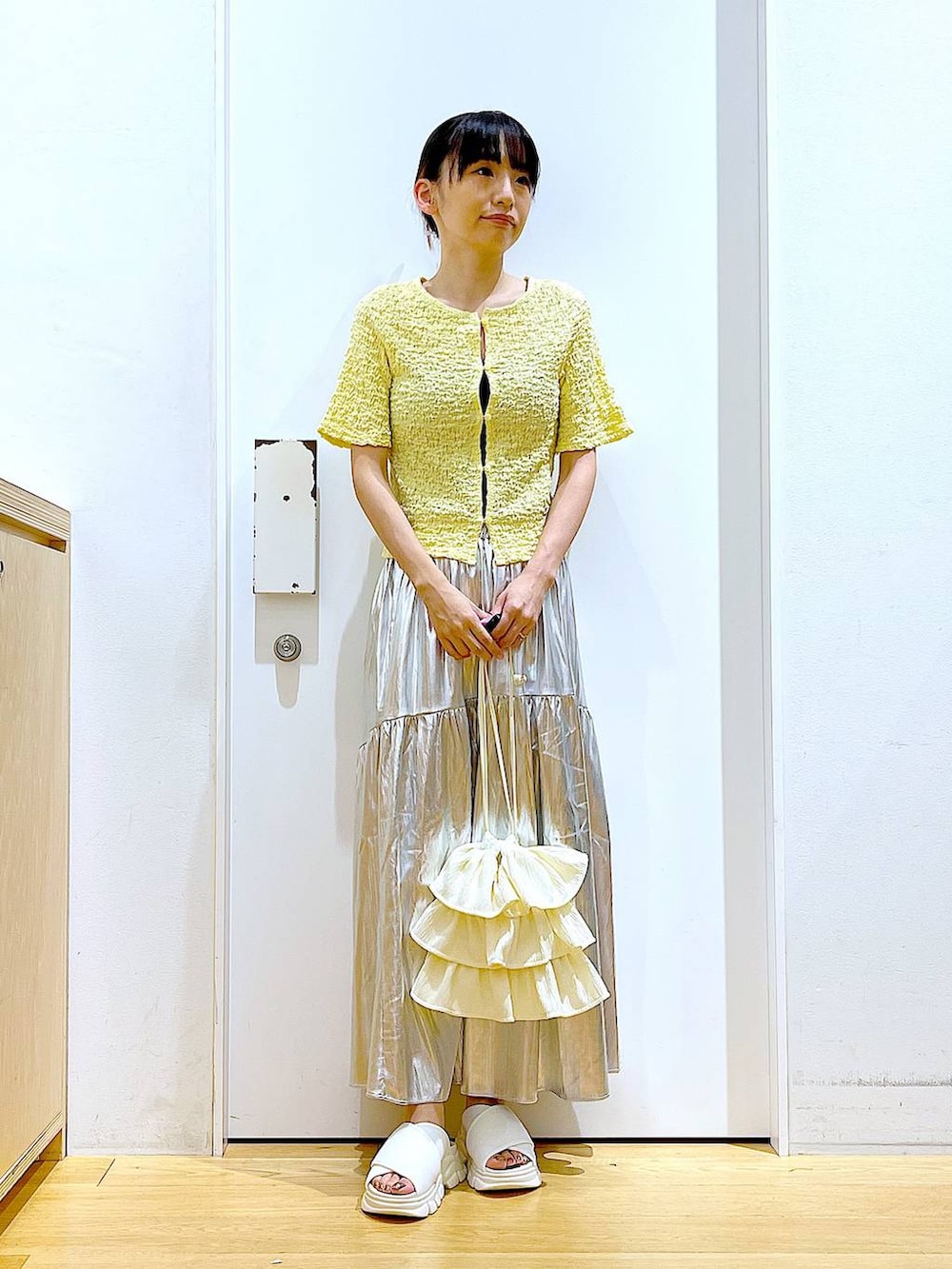 ホワイト系のサンダル、シルバー系のスカート、イエロー系のカーディガン/ボレロを着用したレディースの夏コーディネートの2枚目の写真