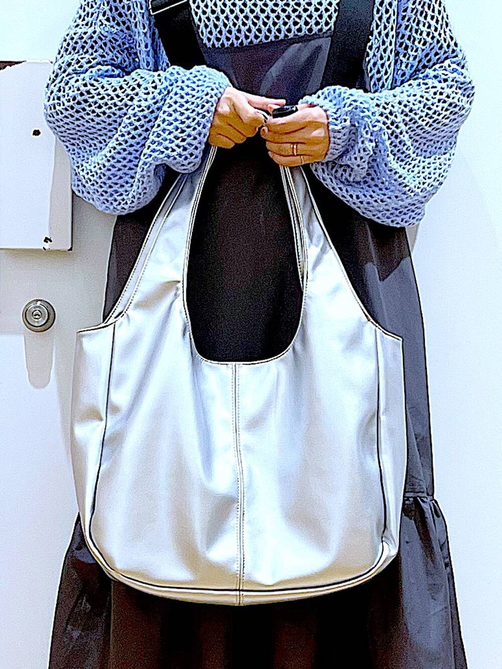 ブラック系のTシャツ/カットソー、ブルー系のニット/セーター、シルバー系のトートバッグを着用したレディースの春コーディネートの9枚目の写真