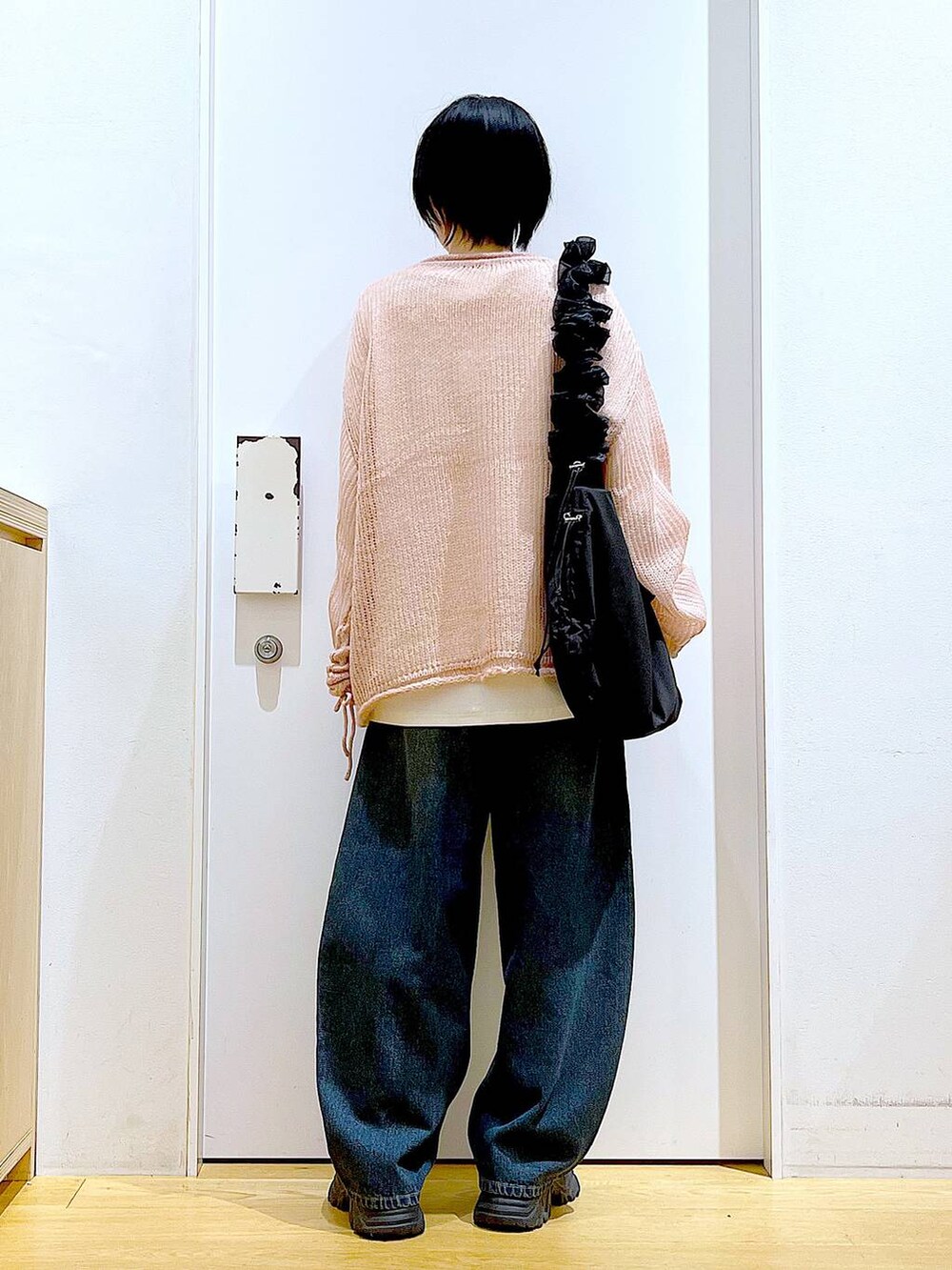 ブラック系のショルダーバッグ、ブラック系のブーツ、ピンク系のニット/セーターを着用したレディースの冬コーディネートの5枚目の写真