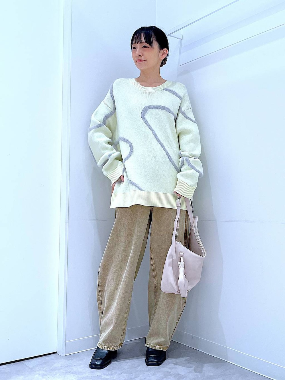 ベージュ系のデニムパンツ、ブラック系のブーツ、ホワイト系のショルダーバッグを着用したレディースの冬コーディネートの2枚目の写真