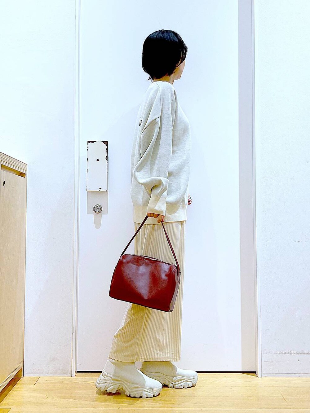 ベージュ系のニット/セーター、レッド系のショルダーバッグ、ベージュ系のブーツを着用したレディースの冬コーディネートの4枚目の写真
