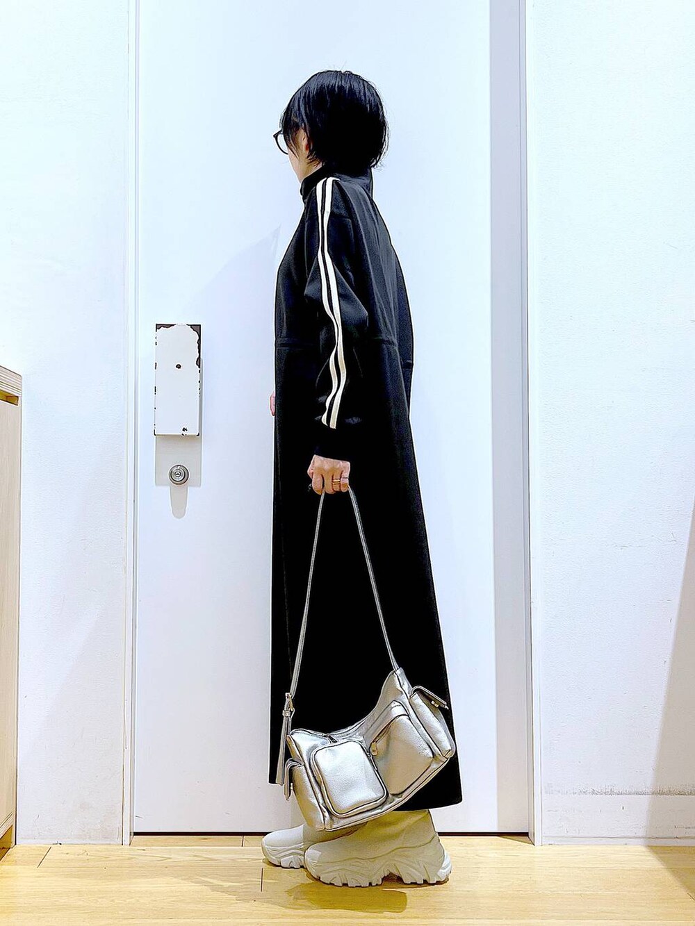 ベージュ系のブーツ、ブラック系のワンピース、その他のショルダーバッグを着用したレディースの秋コーディネートの3枚目の写真