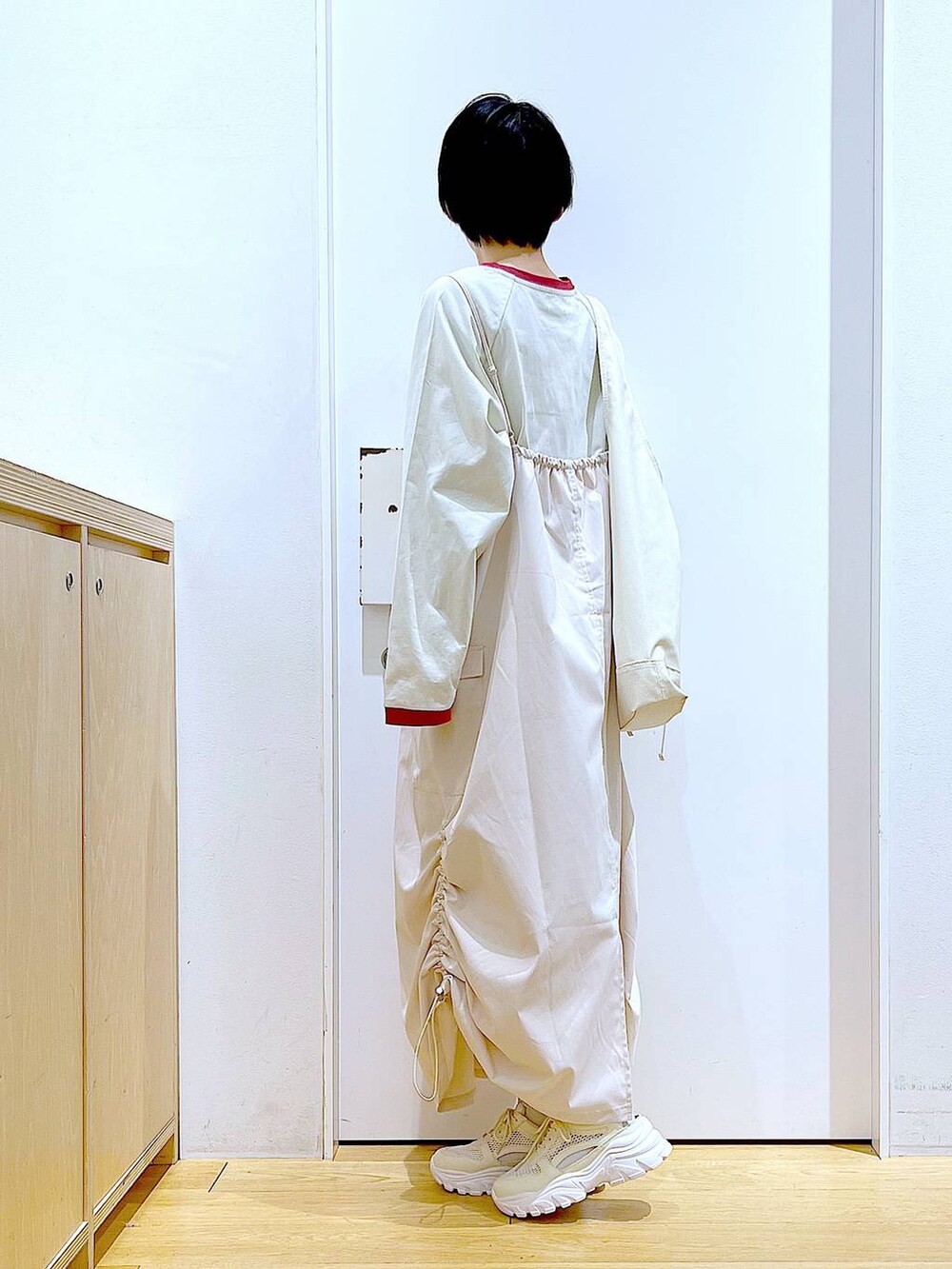 ホワイト系のスニーカー、ベージュ系のジャンパースカート、ベージュ系のTシャツ/カットソーを着用したレディースの春コーディネートの3枚目の写真