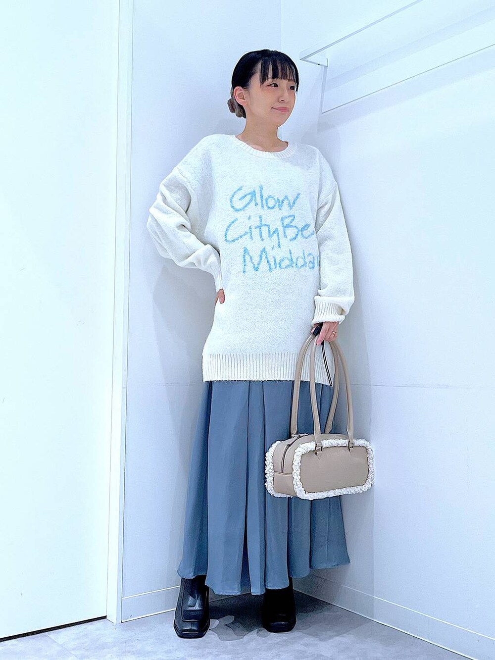 ブラック系のブーツ、ブルー系のスカート、ベージュ系のボストンバッグを着用したレディースの冬コーディネートの2枚目の写真