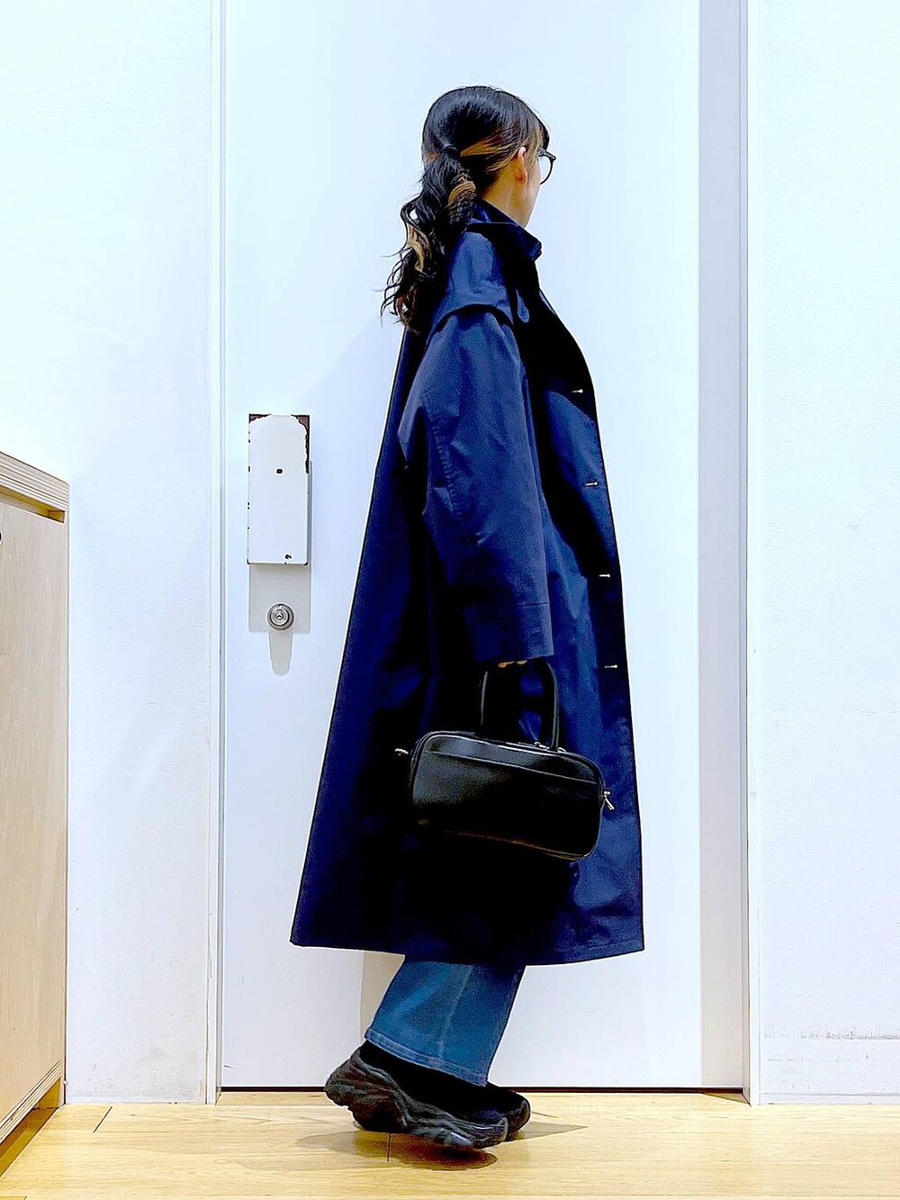 ブラック系のショルダーバッグ、ブルー系のデニムパンツ、ブルー系のその他アウターを着用したレディースの冬コーディネートの4枚目の写真