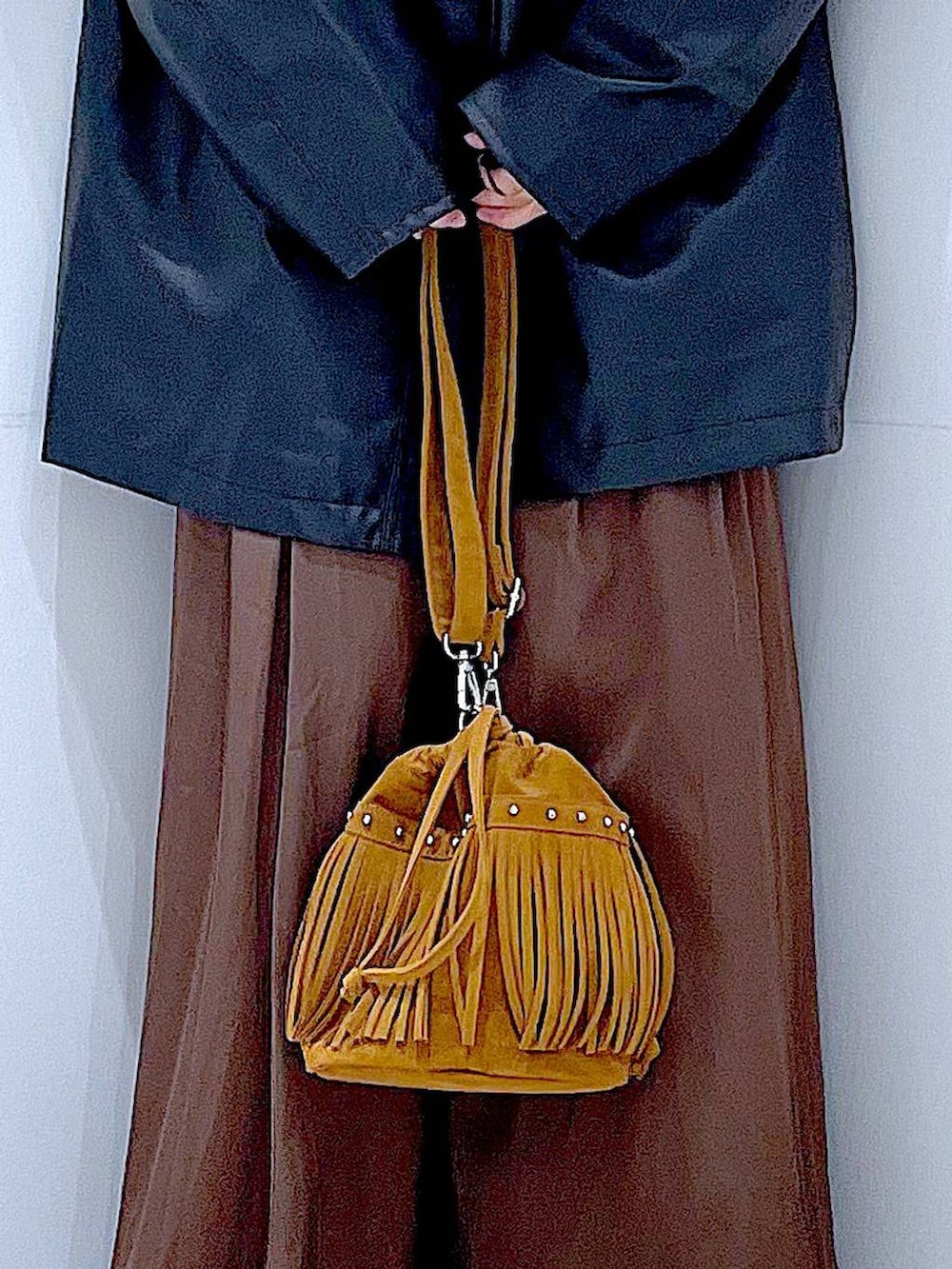 ブラック系のステンカラーコート、レッド系のニット/セーター、ブラック系のブーツを着用したレディースの冬コーディネートの9枚目の写真