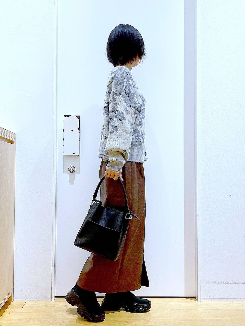 ブラウン系のスカート、ブラック系のショルダーバッグ、ブラック系のブーツを着用したレディースの冬コーディネートの4枚目の写真