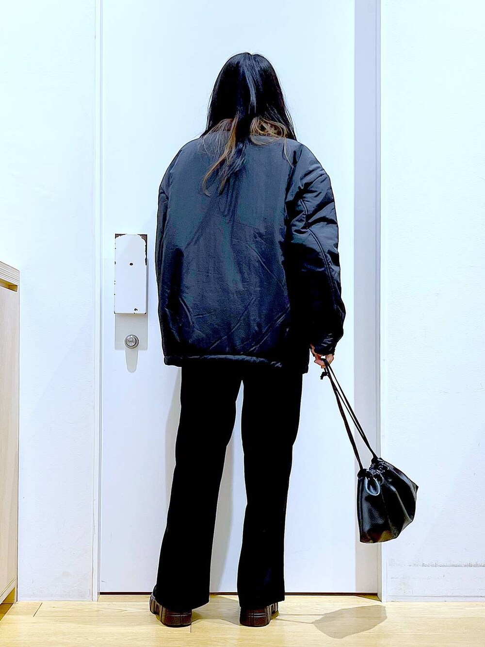 ブラック系のブルゾン、ブラック系のショルダーバッグ、ブラック系のブーツを着用したレディースの冬コーディネートの5枚目の写真