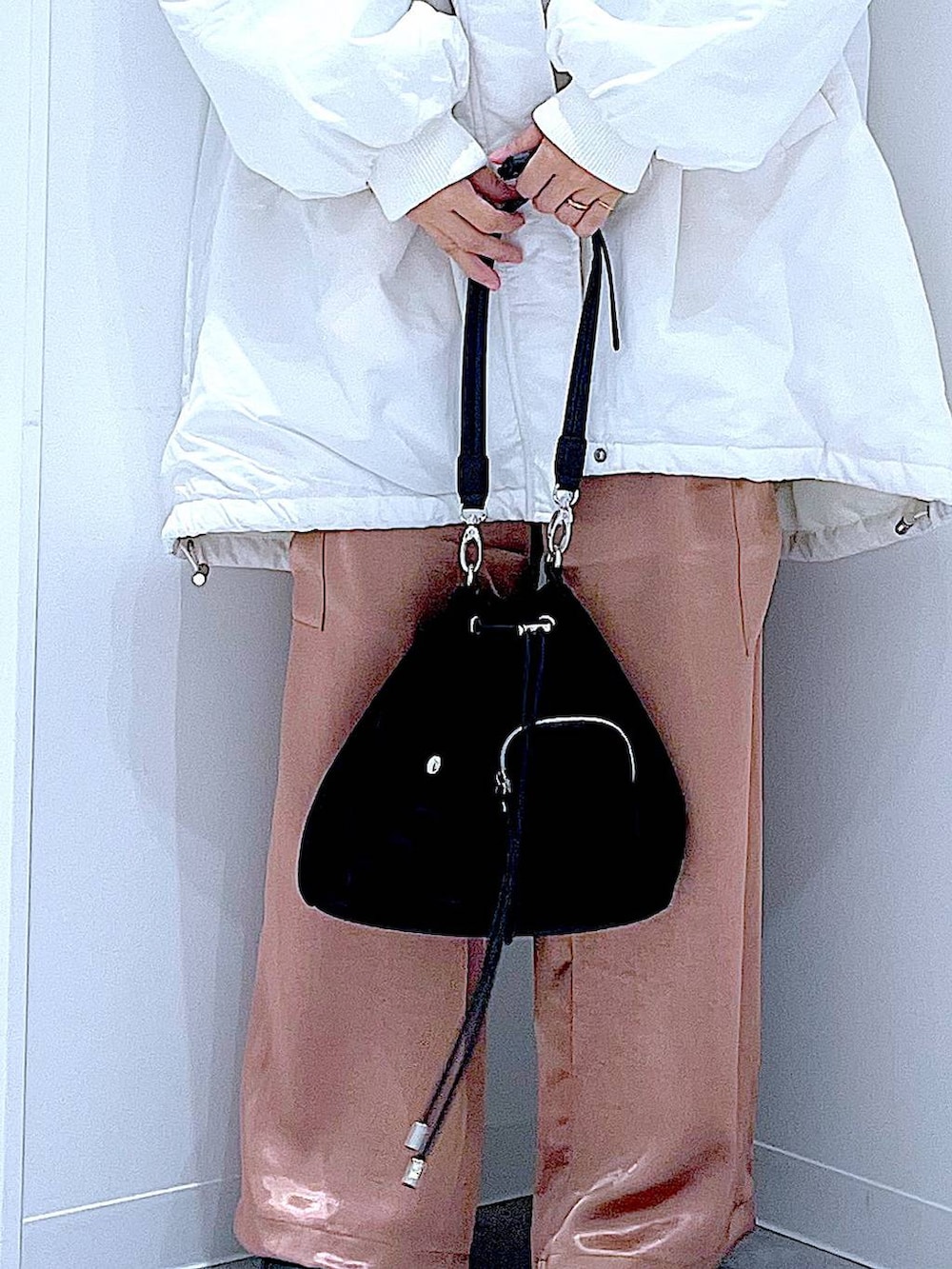 ホワイト系のブルゾン、ブラック系のショルダーバッグ、ブラック系のブーツを着用したレディースの冬コーディネートの9枚目の写真