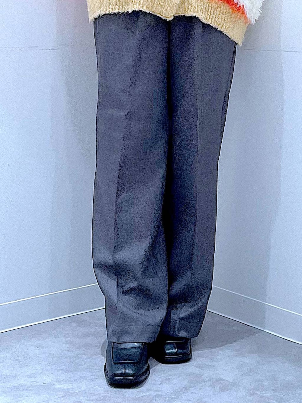 オレンジ系のカーディガン/ボレロ、ブラック系のブーツ、グレー系のスラックスを着用したレディースの冬コーディネートの8枚目の写真