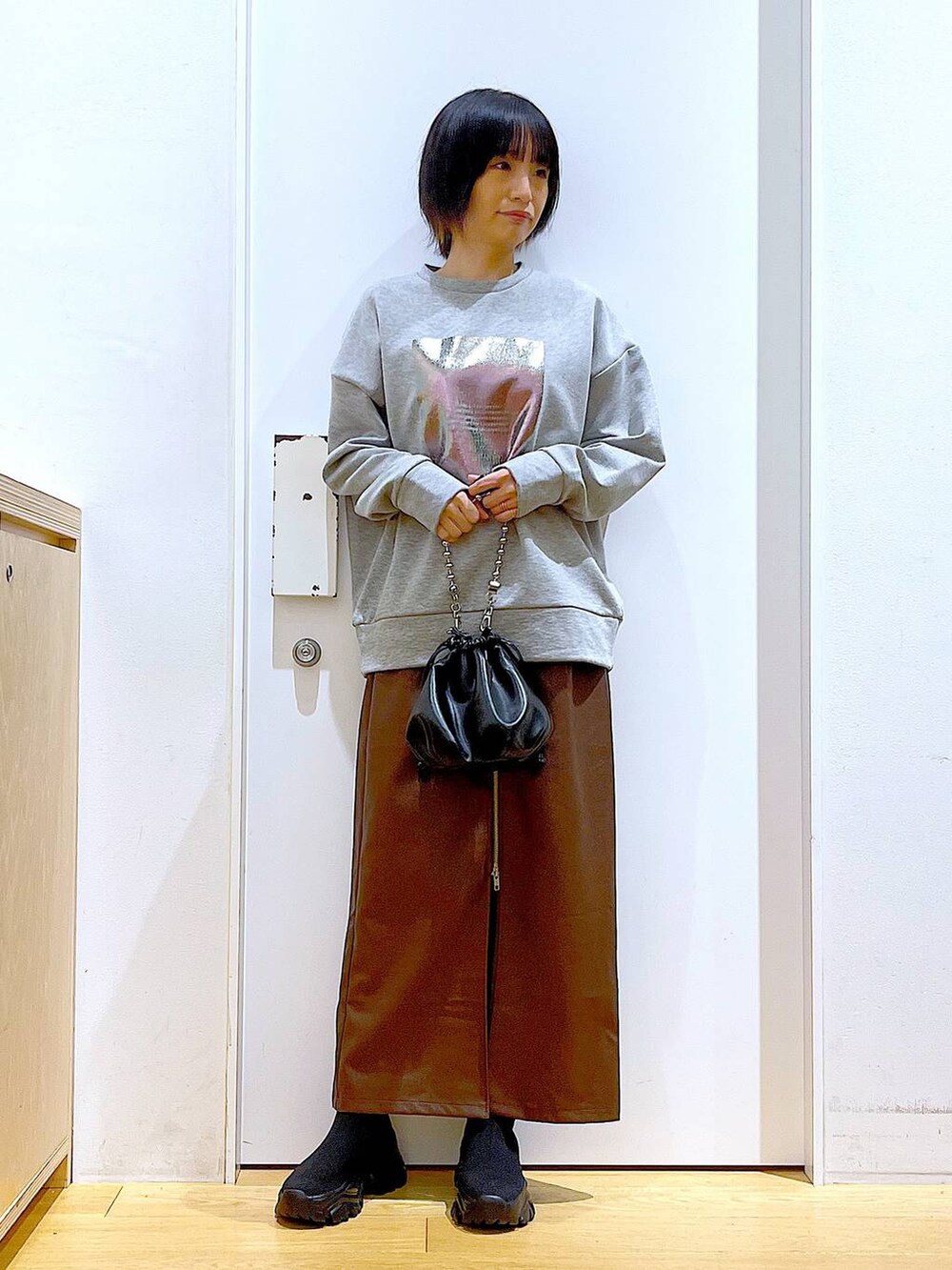 ブラウン系のスカート、ブラック系のショルダーバッグ、ブラック系のブーツを着用したレディースの冬コーディネートの2枚目の写真