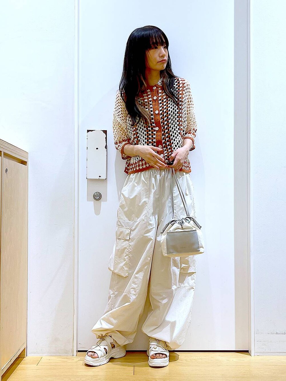 ホワイト系のショルダーバッグ、ホワイト系のカーゴパンツ、ホワイト系のサンダルを着用したレディースの夏コーディネートの2枚目の写真