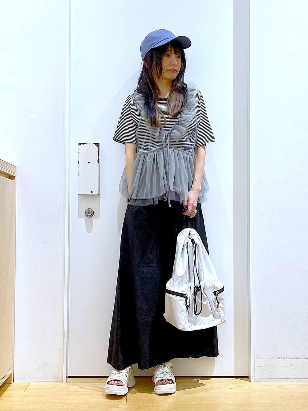 ホワイト系のショルダーバッグ、ホワイト系のサンダル、ブラック系のスカートを着用したレディースの夏コーディネートの2枚目の写真