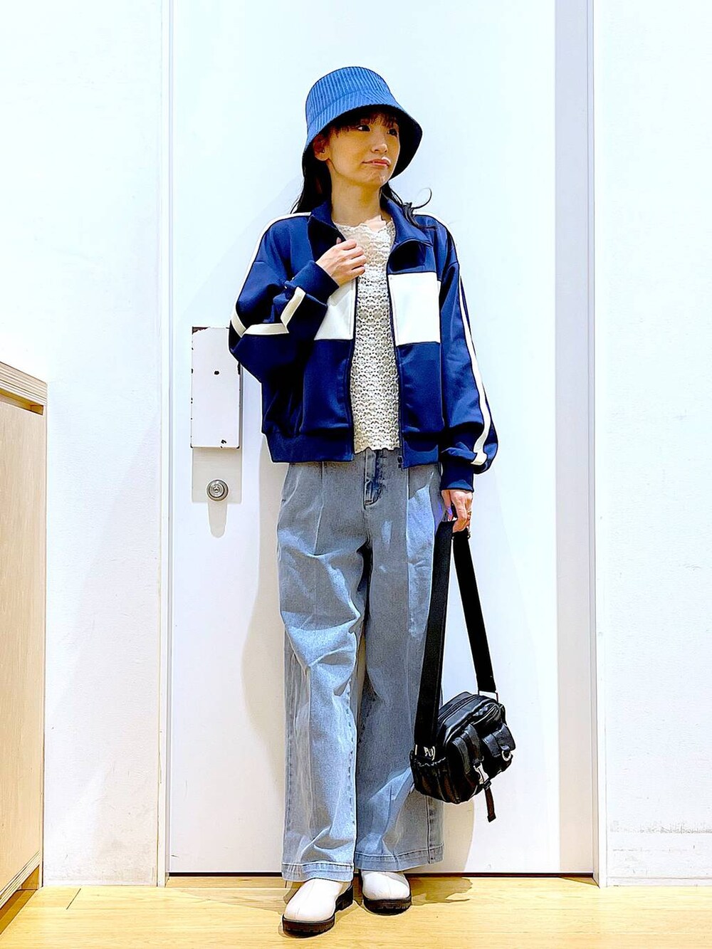 ブルー系のデニムパンツ、ベージュ系のブーツ、ブラック系のショルダーバッグを着用したレディースの冬コーディネートの2枚目の写真