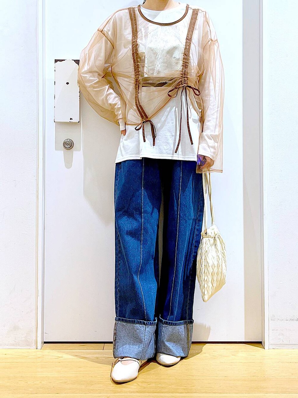 ホワイト系のショルダーバッグ、ホワイト系のパンプス、ブルー系のデニムパンツを着用したレディースの秋コーディネートの6枚目の写真