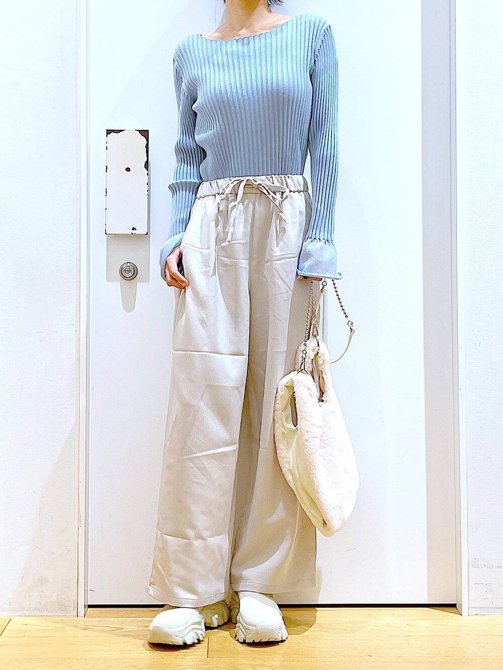 ブルー系のニット/セーター、ホワイト系のショルダーバッグ、ベージュ系のブーツを着用したレディースの冬コーディネートの6枚目の写真