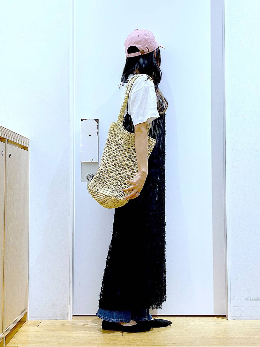 ブルー系のデニムパンツ、ブラック系のワンピース、ブラック系のパンプスを着用したレディースの春コーディネートの4枚目の写真