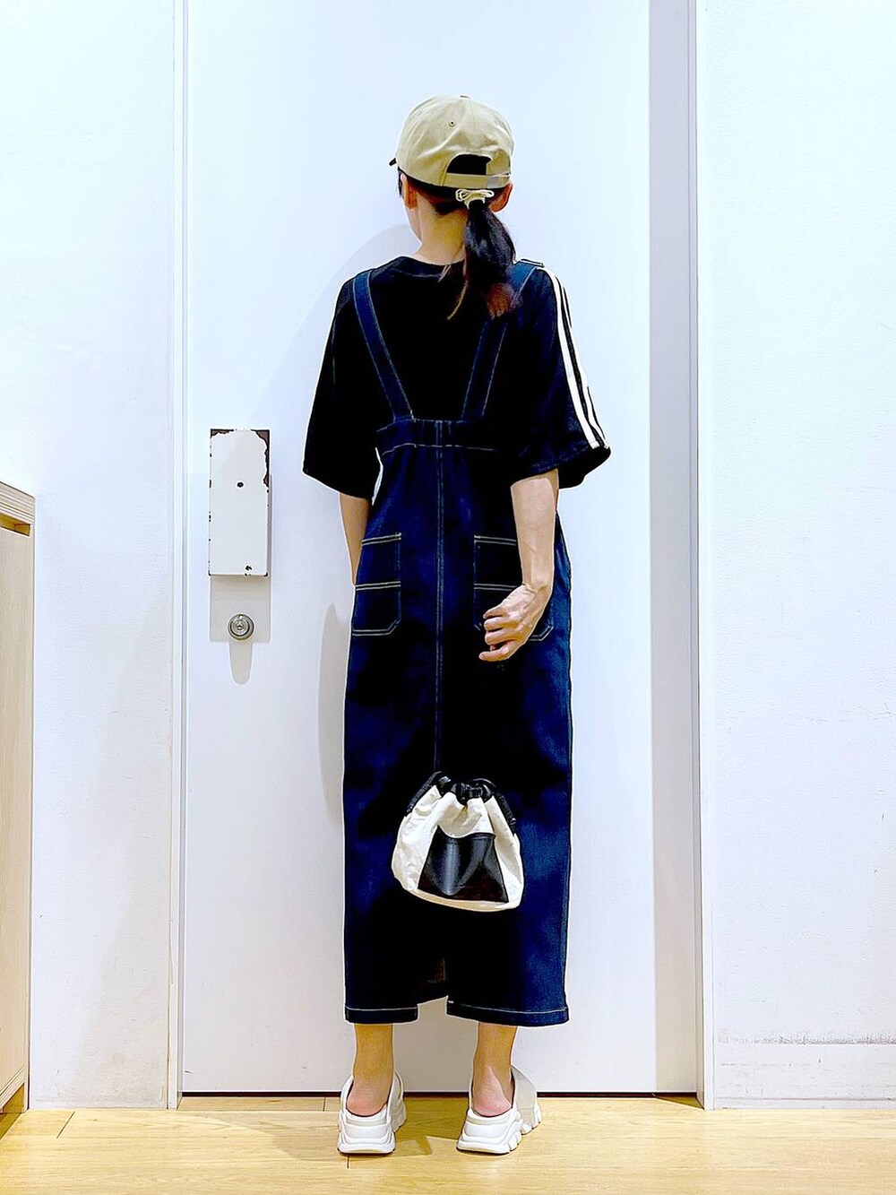 ブルー系のジャンパースカート、ホワイト系のショルダーバッグ、ホワイト系のサンダルを着用したレディースの夏コーディネートの5枚目の写真