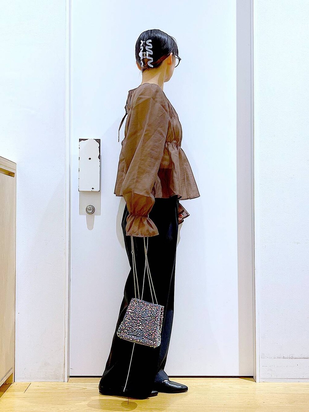 グレー系のショルダーバッグ、ブラック系のスラックス、ブラック系のパンプスを着用したレディースの秋コーディネートの4枚目の写真