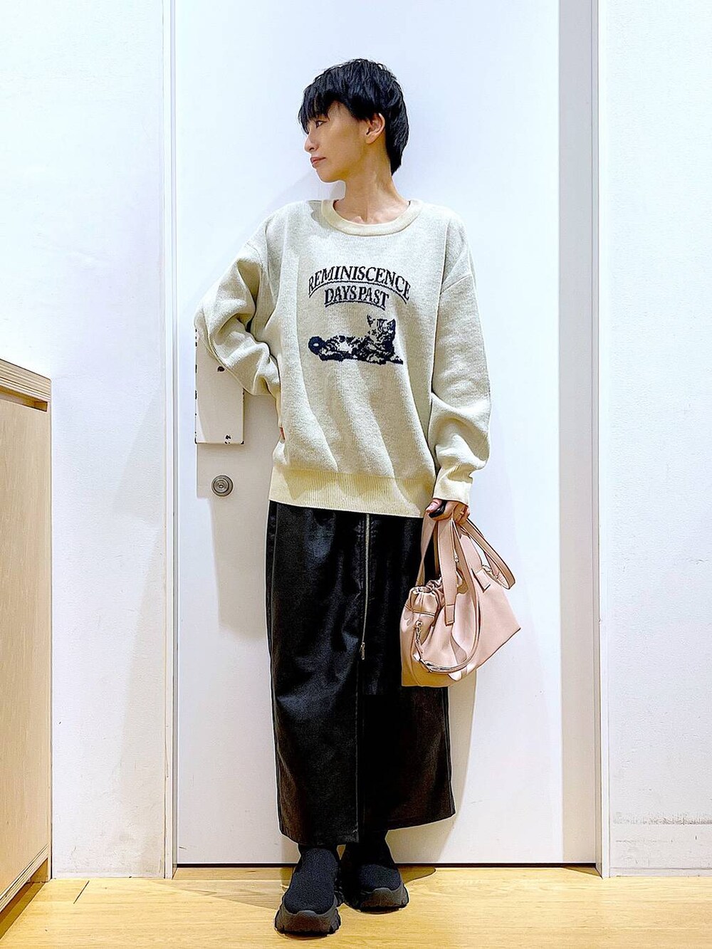 ブラック系のスカート、ブラック系のブーツ、ピンク系のショルダーバッグを着用したレディースの冬コーディネートの2枚目の写真