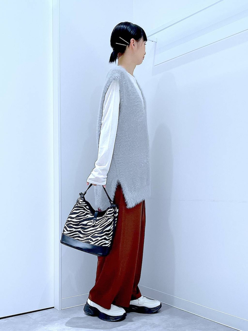 ホワイト系のTシャツ/カットソー、ホワイト系のローファー、グレー系のベストを着用したレディースの秋コーディネートの4枚目の写真