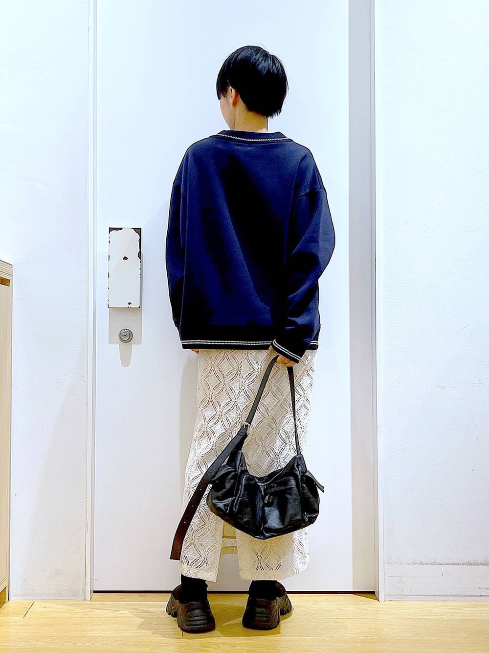 ブラック系のブーツ、ホワイト系のスカート、ブラック系のショルダーバッグを着用したレディースの冬コーディネートの5枚目の写真