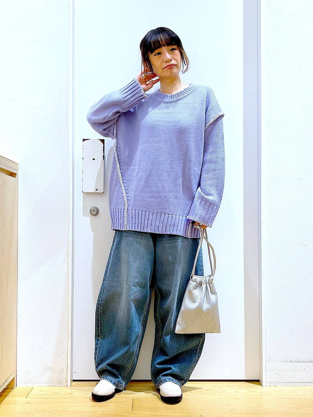 シルバー系のショルダーバッグ、ベージュ系のブーツ、ブルー系のデニムパンツを着用したレディースの冬コーディネートの2枚目の写真