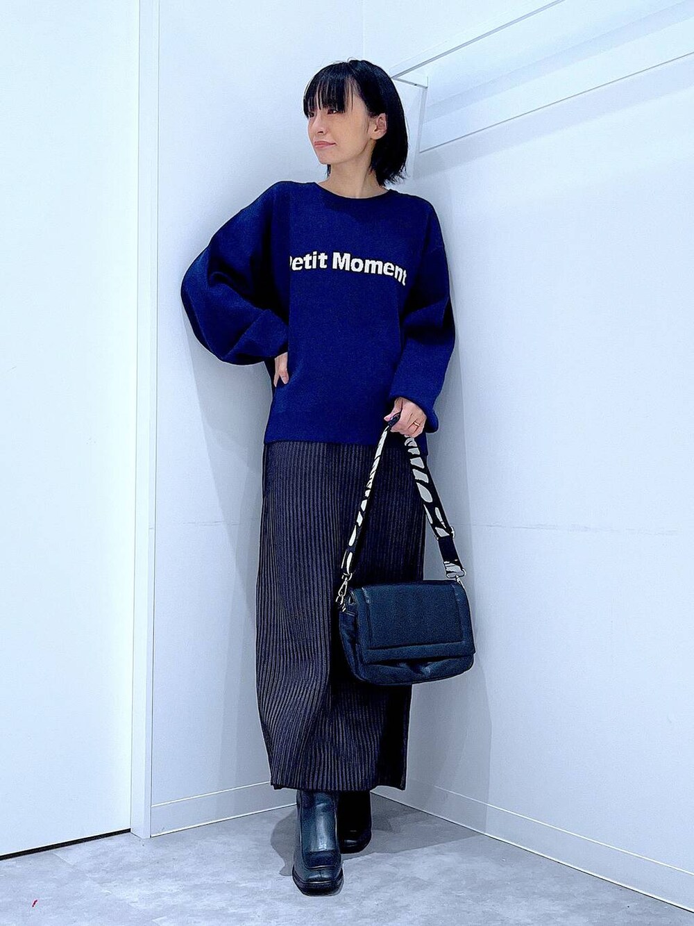 ブラック系のスカート、ブラック系のショルダーバッグ、ブラック系のブーツを着用したレディースの冬コーディネートの2枚目の写真