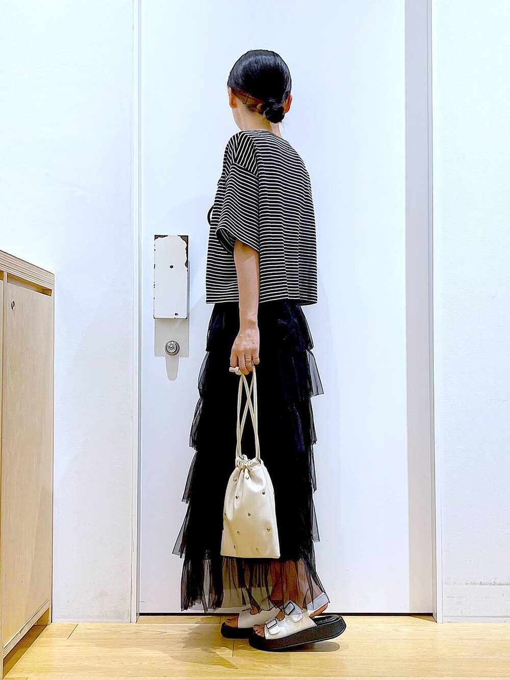 ホワイト系のサンダル、ホワイト系のショルダーバッグ、ブラック系のスカートを着用したレディースの夏コーディネートの3枚目の写真