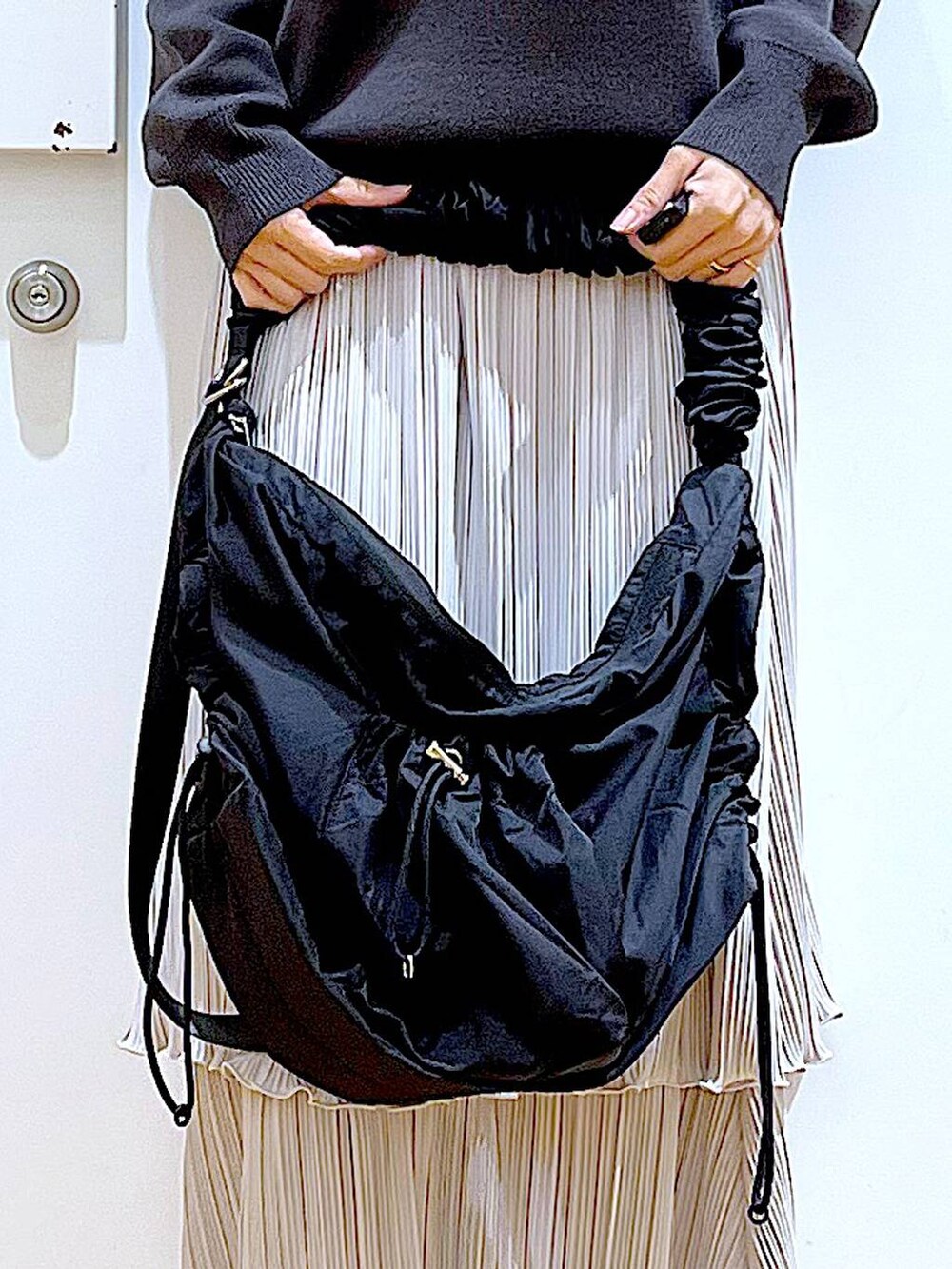 ブラック系のショルダーバッグ、ブラック系のスニーカー、グレー系のニット/セーターを着用したレディースの夏コーディネートの9枚目の写真