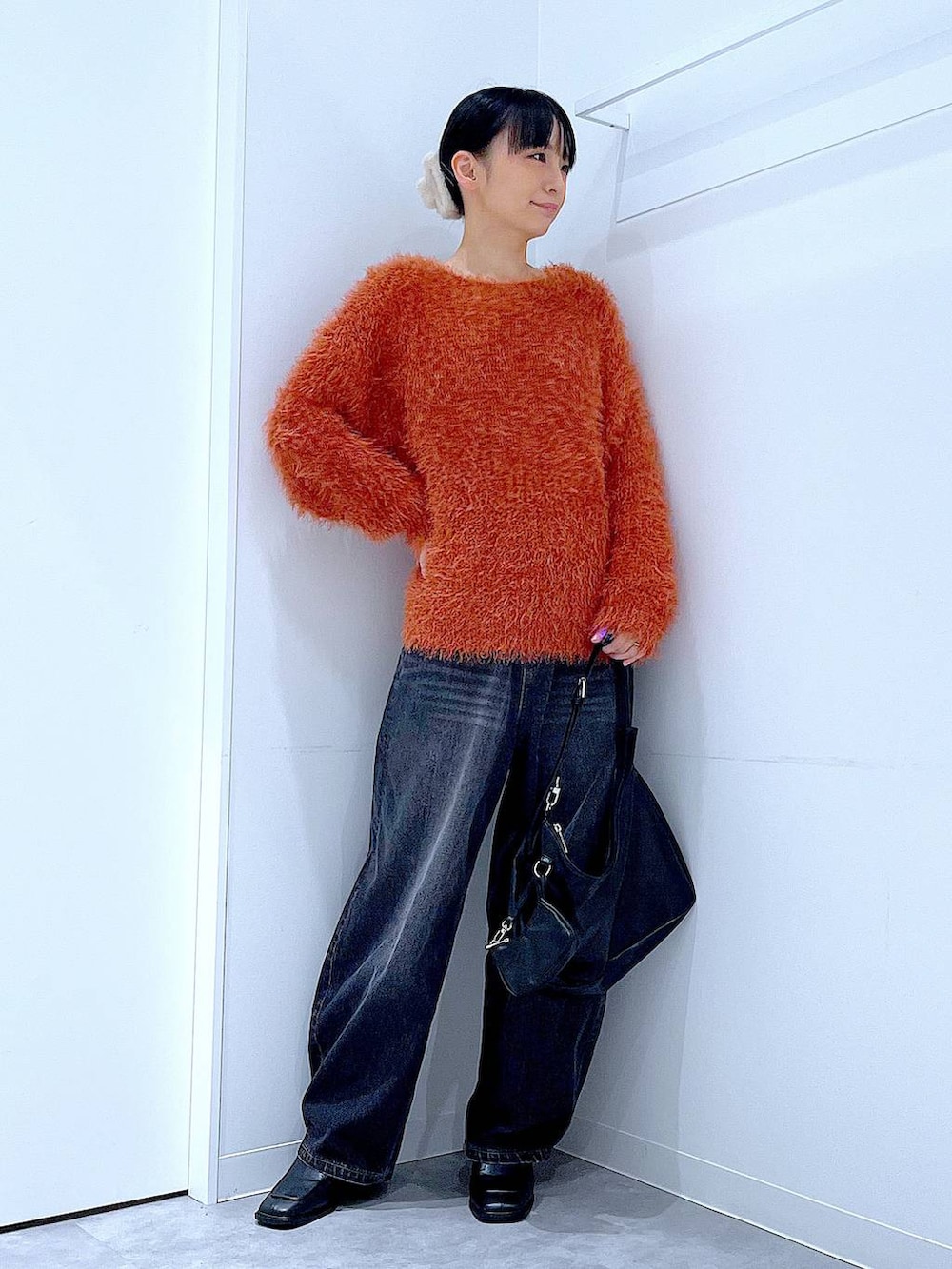 ブラック系のデニムパンツ、ブラック系のブーツ、ブラック系のショルダーバッグを着用したレディースの秋コーディネートの2枚目の写真