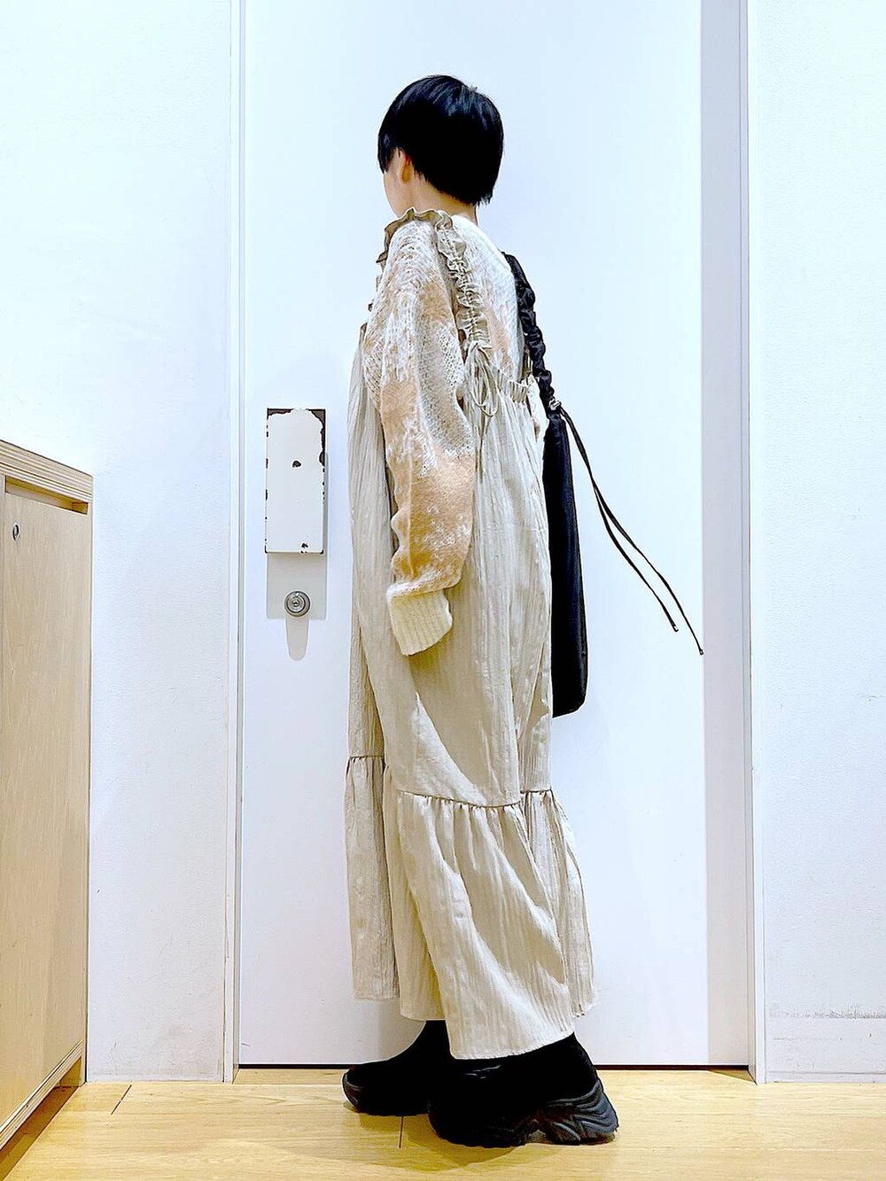 ブラック系のショルダーバッグ、ブラック系のブーツ、ベージュ系のワンピースを着用したレディースの冬コーディネートの3枚目の写真