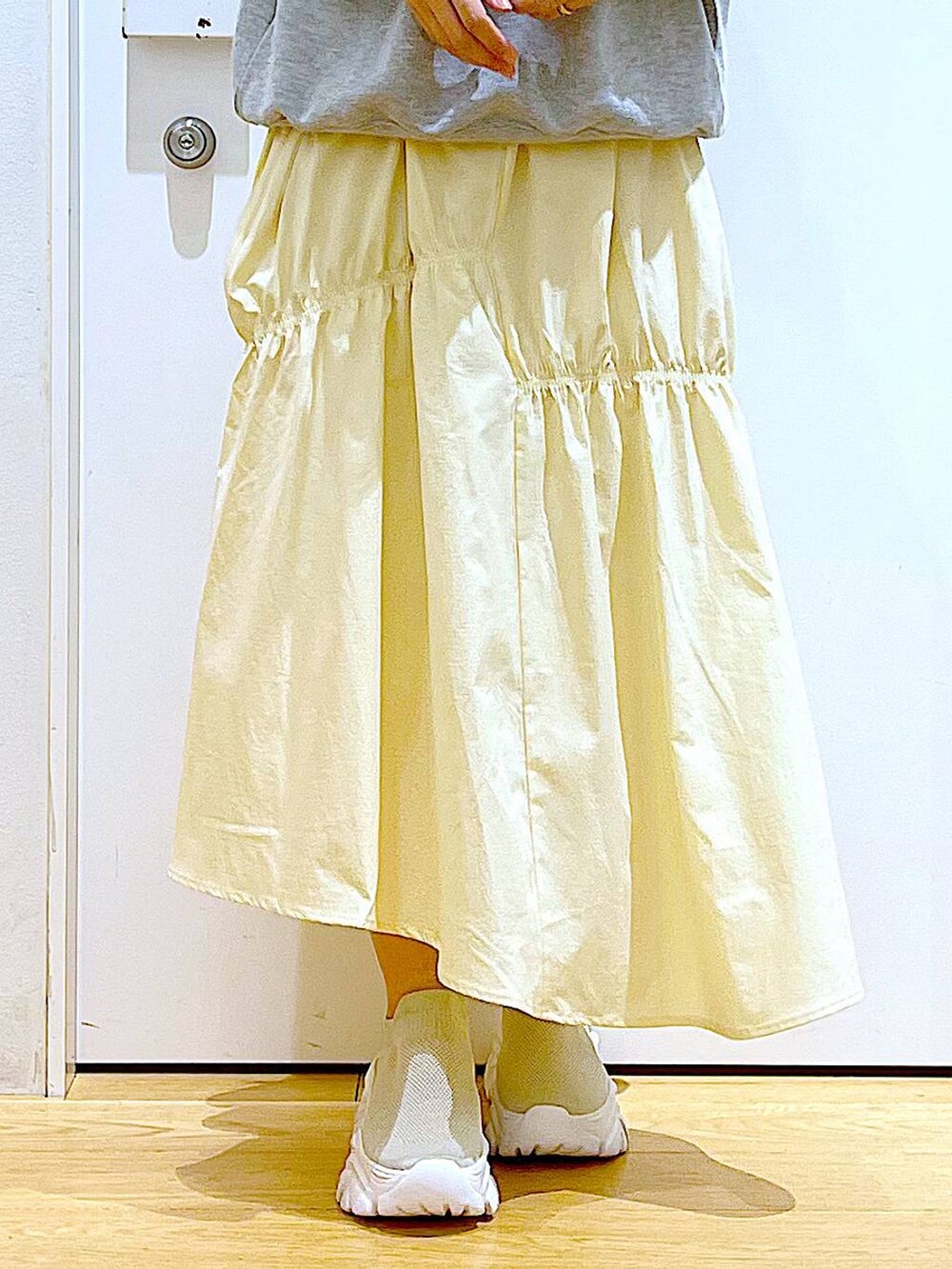 グレー系のスウェット、ベージュ系のスニーカー、イエロー系のスカートを着用したレディースの春コーディネートの8枚目の写真