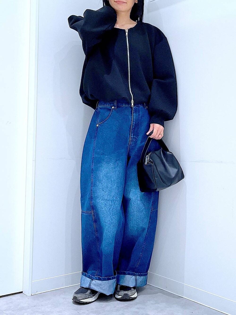 ブラック系のショルダーバッグ、ブルー系のデニムパンツ、ブラック系のスウェットを着用したレディースの春コーディネートの6枚目の写真