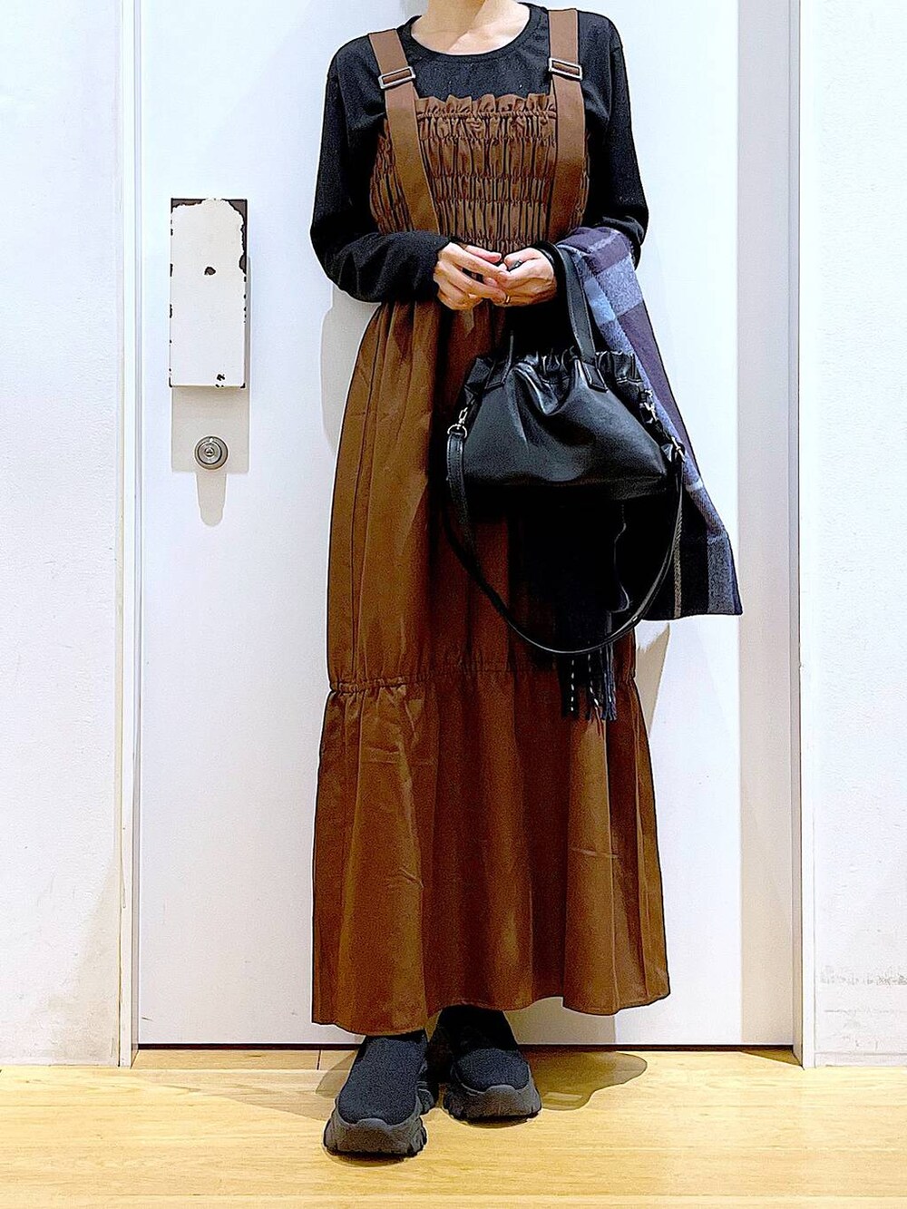 ブラック系のブーツ、ブラウン系のワンピース、ブラック系のショルダーバッグを着用したレディースの冬コーディネートの6枚目の写真