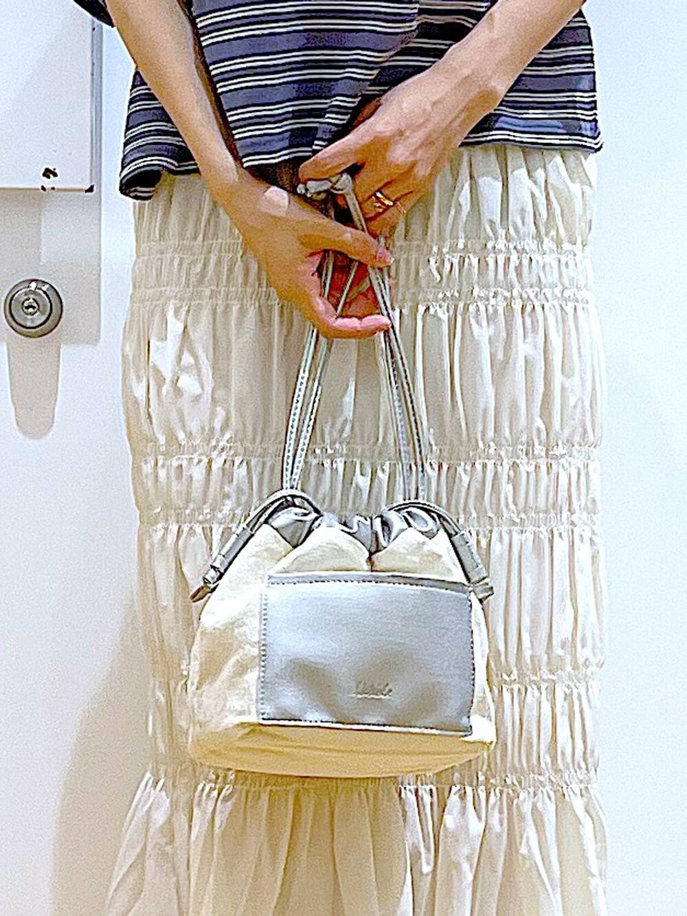 ホワイト系のショルダーバッグ、ホワイト系のサンダル、グレー系のTシャツ/カットソーを着用したレディースの夏コーディネートの9枚目の写真