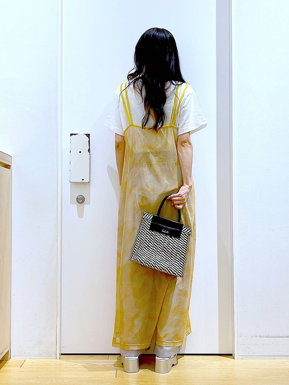 シルバー系のサンダル、オレンジ系のワンピース、ブラック系のショルダーバッグを着用したレディースの夏コーディネートの5枚目の写真