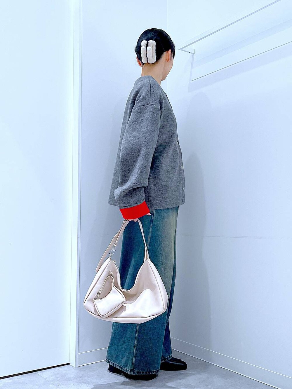 ブルー系のデニムパンツ、ブラック系のブーツ、ホワイト系のショルダーバッグを着用したレディースの冬コーディネートの4枚目の写真