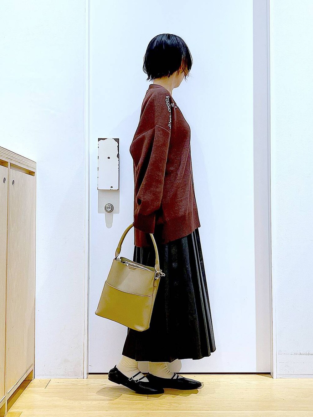 ブラック系のパンプス、ブラック系のスカート、ベージュ系のショルダーバッグを着用したレディースの秋コーディネートの4枚目の写真