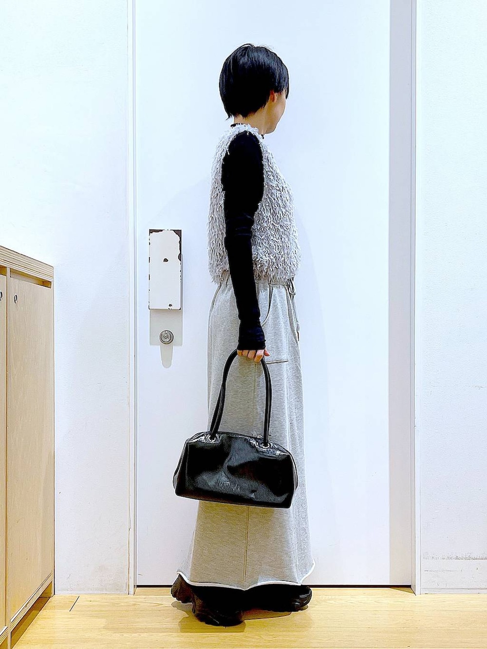 ブラック系のブーツ、ブラック系のTシャツ/カットソー、グレー系のスカートを着用したレディースの春コーディネートの4枚目の写真